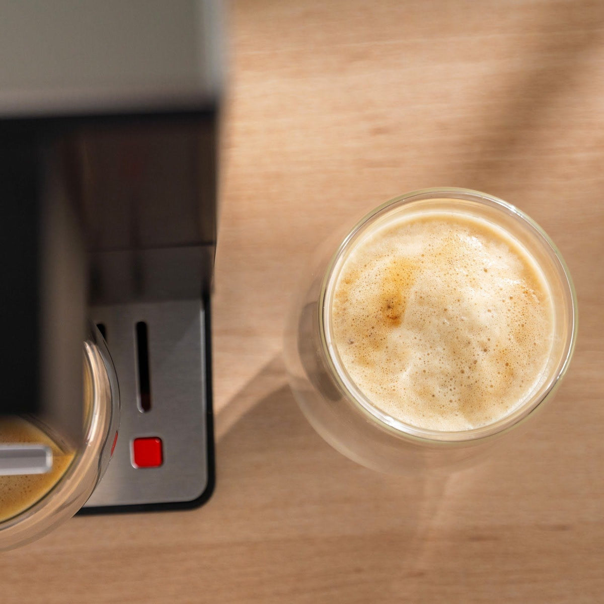Latte i ett glas sett ovanifrån, med ett ljust, tätt lager mjölkskum