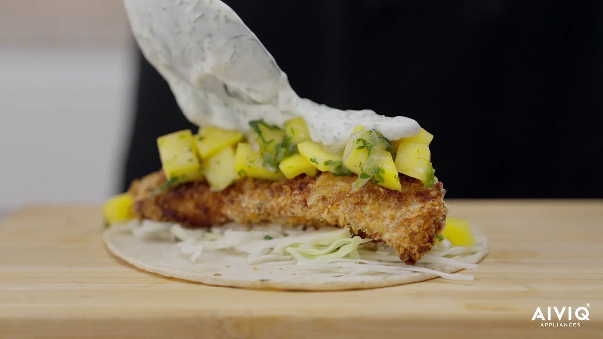 Fisktaco med panerad torsk, mangosallad och örtkräm på en skärbräda