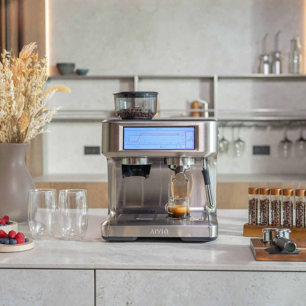 Aspire Expert på en ljus bänkskiva i ett kök med träpaneler och öppna hyllor. En espresso rinner ner i en liten mätbägare medan skärmen visar en tryckkurva.